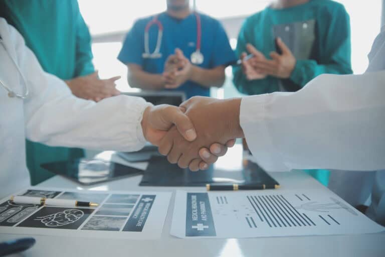 Mature doctors and young nurses stacking hands together at hospi